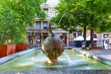 Mainz, Almanya - 19 Haziran 2025: Mainz, Almanya 'da ağaçlar ve tarihi binalarla çevrili küresel bir heykel bulunan sanatsal çeşme, kentteki sükunetin özünü yakalıyor.