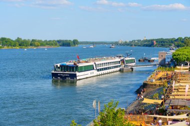 Mainz, Almanya - 19 Haziran 2025: Mainz, Almanya 'da kıyı manzarasının keyfini çıkaran yolcularla dolu bir nehir yolcu gemisi.