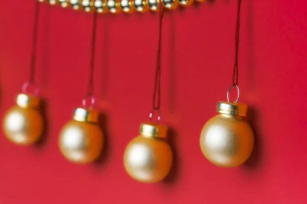 Parlak altın renginde Noel boncuk çelenk stüdyo ışık kırmızı zemin üzerine tarafından dekore edilmiş bir satır asılı beş küçük mat altın renkli Noel süs