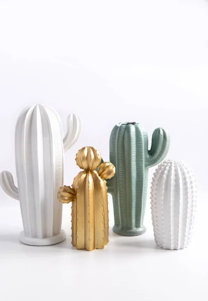 Işık duvara karşı masada trendy kaktüs şeklinde vazolar. Yaratıcı dekor. Modern beyaz, yeşil ve altın boyunda seramik vazo, dekorasyon nesne izole.