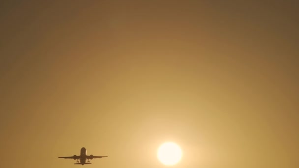 L'avion décolle à l'aube de la piste en arrière-plan du soleil au coucher du soleil dans les rayons de lumière jaune. L'avion nettoie le châssis en augmentant la hauteur et la vitesse .