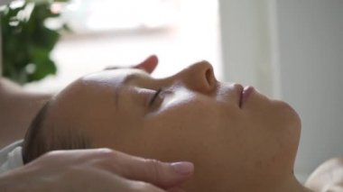 Güzellik salonunda kozmetik tedavisi gören bir kadın. Kozmetik uzmanı tıp eldivenleri kızın yüzüne dokunuyor. Profesyonel masajla yüz temizleme. Vücut ve cilt bakımı, sağlık, refah..