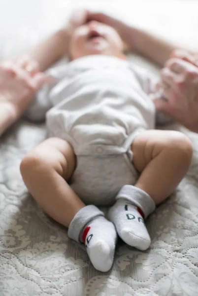 Yeni doğan sırt üstü yatıyor ve ailesi, babası ve annesi ellerini tutuyor. Yeni bir hayat. Çocuklar ve hamilelik. Bebek ve Mutlu ebeveynler. İnsan ırkının devamı.