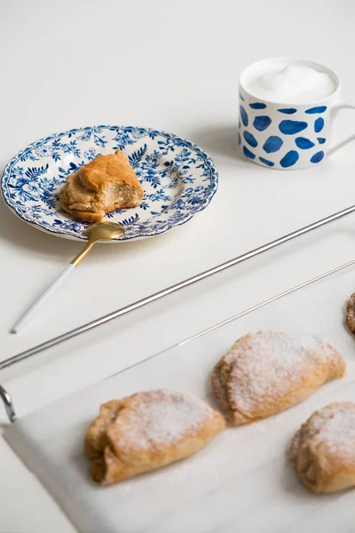 Mavi tabaklarda lezzetli ev yapımı tatlı. Beyaz bir kupa kahve ile Shortbread tatlı. çay kaşığı altın. Yaprak küpeli tabak. Beyaz arka planda.