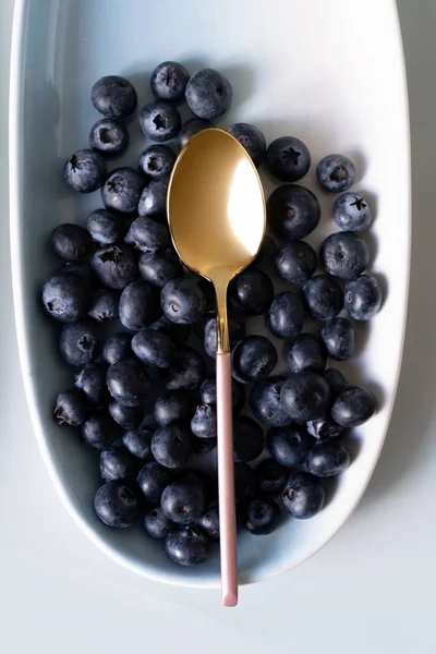 Pembe çay kaşığı ile mavi renklerin yeni zarif tabaklarda Yaz meyveleri yaban mersini. İzole beyaz arka plan üzerinde yukarıdan yeni lüks Altın çatal görünümü. Üstte görüntü.