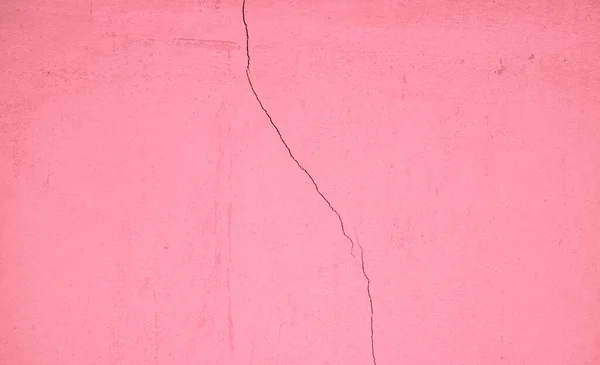 Pastel pembe beton duvar yüzeyi, çatlaklarla ve çiziklerle yıpranmış, arka plan için soyut doku