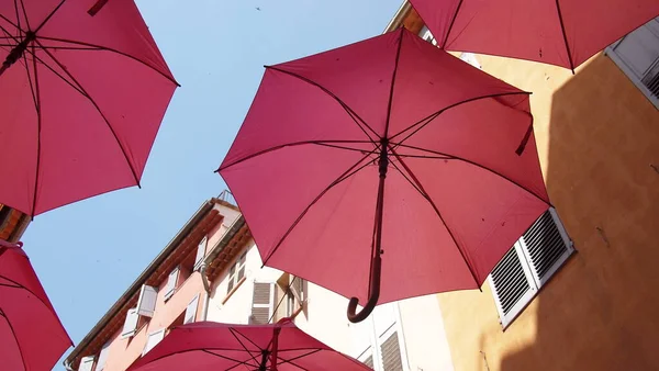 Elements of architecture of Grasse with pink umbrellas between houses, France