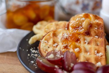 yakın çekim. Fitness waffle ücretsiz gluten ve şeker. bir elektrikli tost makinesi içinde pişmiş. taze üzüm ve badem ve fındık ile kayısı reçeli