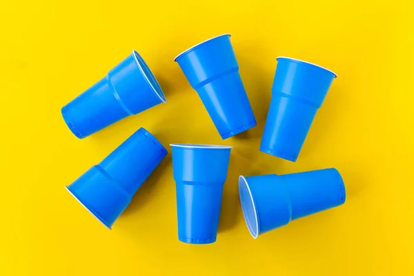 Vibrant blue plastic cups on yellow background.
