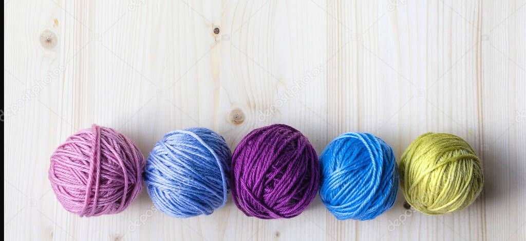 Multicolored woolen balls on wooden background. Banner.