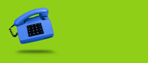 Niebieski telefon stacjonarny na zielonym tle. Sztandar. — Zdjęcie stockowe