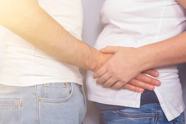 Esposo sosteniendo esposas vientre embarazada. Luz solar . — Foto de Stock