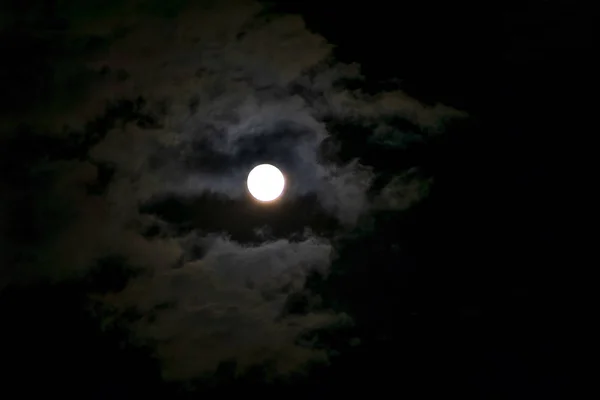 The clouds cover the moon in the night sky