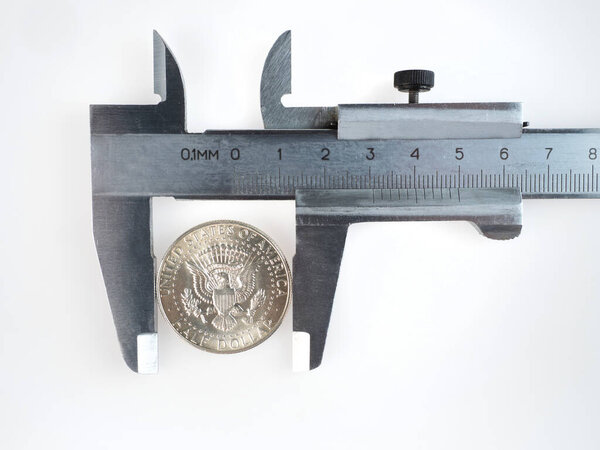 a metal caliper with silver coin isolated on white background