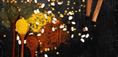 Siyah desenli bir masada çok renkli baharatlı ahşap kaşıklar. mutfak için arkaplan