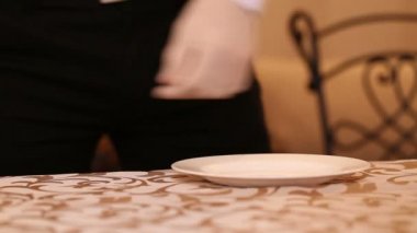 Bir garson plaka, bıçak, çatal ve kristal bardak düzenler. Şenlikli bir yemek için çatal bıçak seti