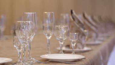 Bir garson plaka, kristal bardak, çatal ve bıçak setleri ile ziyafet için hazırlanan yemek peçeteye düzenler