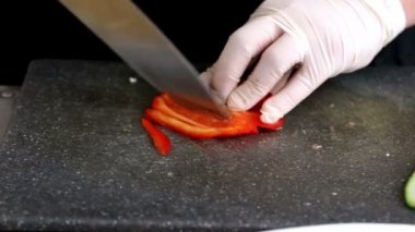 Şef kırmızı biber dilimleri kesme tahtası üzerinde bıçakla keser