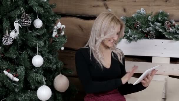 一位女仆正在网上用平板电脑做圣诞购物 圣诞气氛 冷杉点缀白色玩具 寒假的其他装饰 — 图库视频影像
