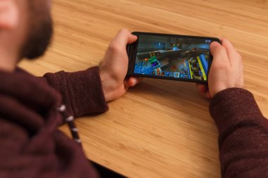 Prague, Çek Cumhuriyeti - 16 Mart 2019: Minecraft mobil oyun tutan bir smartphone ve kelepçelememz adam. Bir bambu zemin üzerine açıklayıcı bir editoryal görüntü.