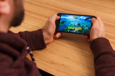 Prague, Çek Cumhuriyeti - 16 Mart 2019: bir akıllı telefon ve kelepçelememz Playerunknown s Battlegrounds Pubg mobil oyun tutan adam. Bir bambu zemin üzerine açıklayıcı bir editoryal görüntü.