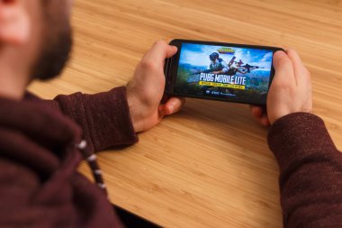 Prague, Çek Cumhuriyeti - 16 Mart 2019: bir akıllı telefon ve kelepçelememz Playerunknown s Battlegrounds Pubg mobil oyun tutan adam. Bir bambu zemin üzerine açıklayıcı bir editoryal görüntü.