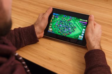 Prague, Çek Cumhuriyeti - 16 Mart 2019: bir akıllı telefon ve kelepçelememz klanlar çatışma mobil oyun tutan adam. Bir bambu zemin üzerine açıklayıcı bir editoryal görüntü.