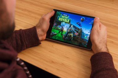 Prague, Çek Cumhuriyeti - 16 Mart 2019: bir akıllı telefon ve kelepçelememz Fortnite tutan adam: Battle Royale mobil oyun. Bir bambu zemin üzerine açıklayıcı bir editoryal görüntü.