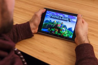 Prague, Çek Cumhuriyeti - 16 Mart 2019: Minecraft mobil oyun tutan bir smartphone ve kelepçelememz adam. Bir bambu zemin üzerine açıklayıcı bir editoryal görüntü.