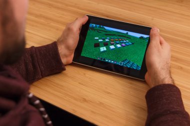 Prague, Çek Cumhuriyeti - 16 Mart 2019: Minecraft mobil oyun tutan bir smartphone ve kelepçelememz adam. Bir bambu zemin üzerine açıklayıcı bir editoryal görüntü.