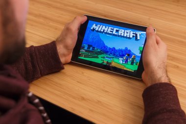 Prague, Çek Cumhuriyeti - 16 Mart 2019: Minecraft mobil oyun tutan bir smartphone ve kelepçelememz adam. Bir bambu zemin üzerine açıklayıcı bir editoryal görüntü.