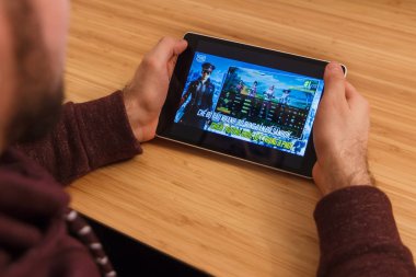 Prague, Çek Cumhuriyeti - 16 Mart 2019: bir akıllı telefon ve kelepçelememz Playerunknown s Battlegrounds Pubg mobil oyun tutan adam. Bir bambu zemin üzerine açıklayıcı bir editoryal görüntü.