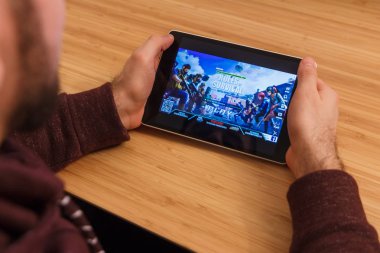 Prague, Çek Cumhuriyeti - 16 Mart 2019: bir akıllı telefon ve kelepçelememz hayatta kalma kuralları mobil oyun tutan adam. Bir bambu zemin üzerine açıklayıcı bir editoryal görüntü.