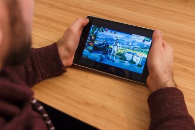 Prague, Çek Cumhuriyeti - 16 Mart 2019: bir akıllı telefon ve kelepçelememz hayatta kalma kuralları mobil oyun tutan adam. Bir bambu zemin üzerine açıklayıcı bir editoryal görüntü.