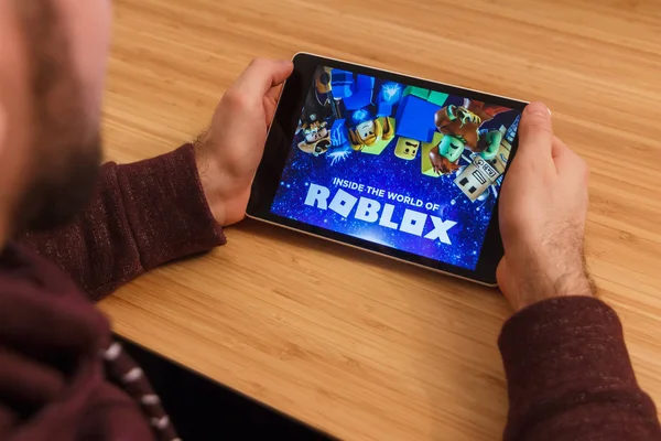 PRAGUE, RÉPUBLIQUE TCHÈQUE - 16 MARS 2019 : Homme tenant un smartphone et jouant au jeu mobile Roblox. Une image éditoriale illustrative sur fond de bambou . — Photo