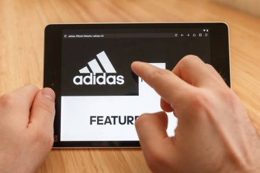 San Francisco, ABD-1 Nisan 2019: internet kullanarak ve Adidas Web sitesi aracılığıyla görünümlü tablet tutarak eller yakın, San Francisco, Kaliforniya, ABD. Açıklayıcı bir editoryal görüntü.