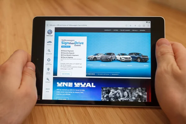 San Francisco, ABD-1 Nisan 2019: internet kullanarak ve VW Web sitesi aracılığıyla görünümlü tablet tutarak eller yakın, San Francisco, Kaliforniya, ABD. Açıklayıcı bir editoryal görüntü.