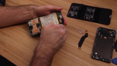 Teknisyen ya da mühendis onarım veya bambu masasında yeni akıllı telefon pili yerine bileşenleri kırık Smartphone sökülmesi