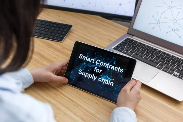 Business Female Using Smart Contracts For Supply chain. Illustration of Ethereum Blockchain on the Screen of Tablet, PC and Laptop.