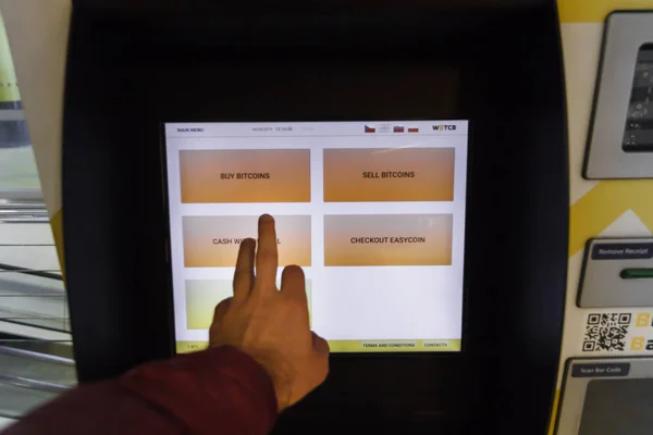 Чехия - 18 мая 2019 года: банкомат биткойна для покупки и продажи криптовалюты. Мужчина покупает биткоины через банкомат, Прага, Чехия. Иллюстративное редакционное изображение — стоковое фото