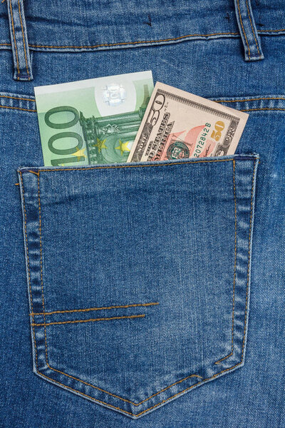 Close Up View to 100 euro and 50 dollar Banknotes Sticking Out From a Blue Jeans Pocket