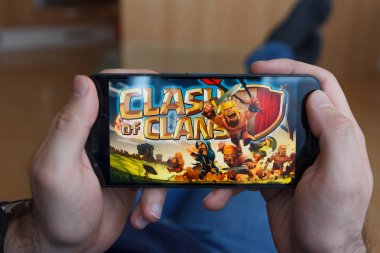 Los Angeles, Kaliforniya-3 Haziran 2019: bir akıllı telefon tutan adam yalan ve akıllı telefon ekranında klanlar ve Fortnite oyunları Clash karşılaştırır. Açıklayıcı bir editoryal görüntü.