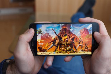 Los Angeles, Kaliforniya-3 Haziran 2019: bir akıllı telefon tutarak ve akıllı telefon ekranında Fortnite oyunu oynarken yalan adam. Açıklayıcı bir editoryal görüntü.