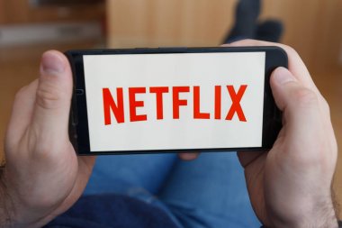 Los Angeles, Kaliforniya-3 Haziran 2019: Netflix izlerken akıllı telefon tutan erkek ellere yakın. Açıklayıcı bir editoryal görüntü