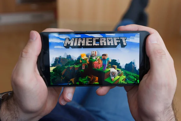Los Angeles, Kaliforniya-3 Haziran 2019: bir akıllı telefon tutarak ve akıllı telefon ekranında Minecraft oyunu oynarken adam yalan. Açıklayıcı bir editoryal görüntü.