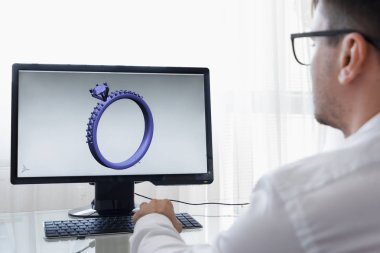 LOS ANGELES, CALIFORNIA - JUNE 3, 2019: Engineer, Constructor, Designer, Architect in Glasses Working on a Personal Computer. He Creating New Design of Golden Ring in CAD Program. Freelance Work. An clipart