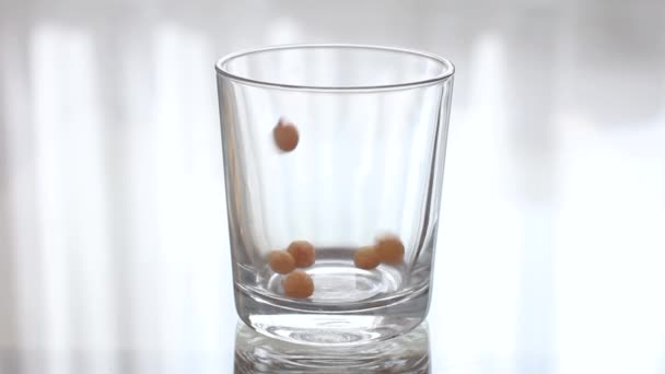 Жареные яйца наливаются в прозрачное пустое стекло. Выливая крупы в прозрачный стакан — стоковое видео
