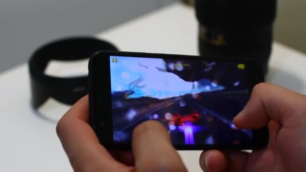 Закройте мужские руки к смартфону Верну. играют в мобильную игру Asphalt 9. Мужчина использует смартфон для игры в Asphalt 9 . — стоковое видео