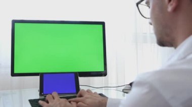 Los Angeles, Kaliforniya-3 Haziran 2019: mühendis, yapıcı, gözlük tasarımcı cam mockup şablonu için Chroma anahtar büyük olan monitör üzerinde yeşil ekran ile bir kişisel bilgisayar üzerinde çalışma. Erkek