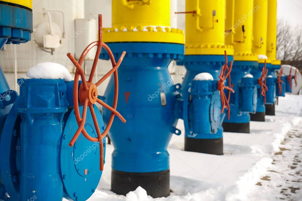 The valves for opening and closing the gas supplying at the gas compressor station in winter. Blue tubes for gas transportation at gas compressor station with red valves for turn on off gas supplying.